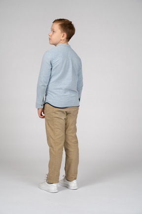 Вид сзади на мальчика в повседневной одежде, смотрящего в сторону