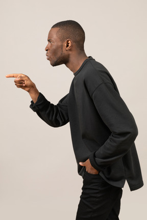 Side view of confused young man pointing