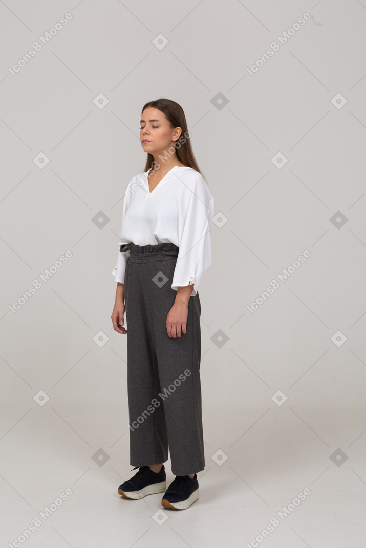 Three-quarter view of a young lady in office clothing standing with her eyes closed