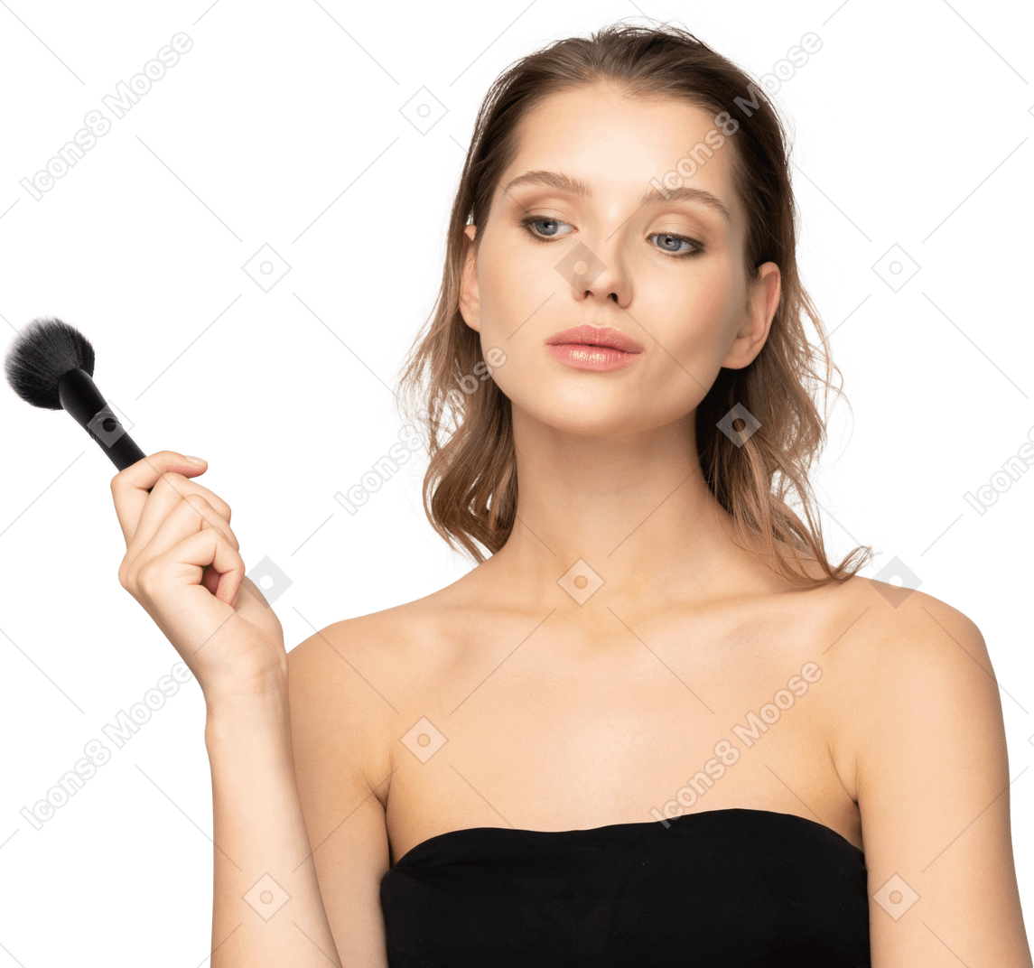 Front view of a thoughtful sensual young woman holding a make-up brush