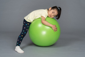 胃の上の緑のフィットボールに横たわっている少女