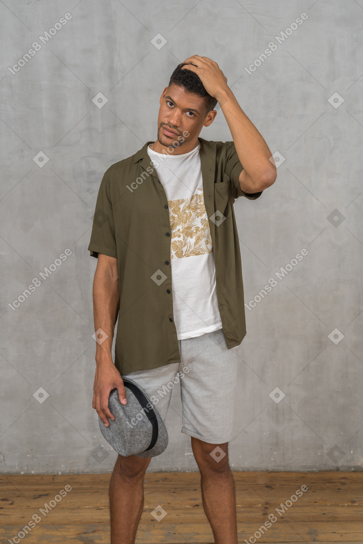 Junger mann posiert mit der hand auf dem kopf
