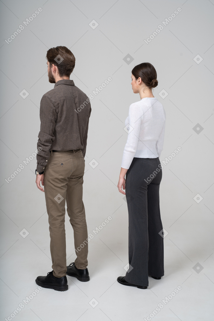 静止しているオフィスの服を着た認識できない若いカップルの4分の3の背面図