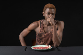 Front view of a thoughtful young afro man sitting at the table
