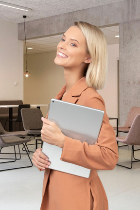 A smiling woman standing in a room with a tablet