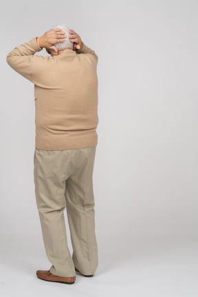Rear view of an old man standing with hands behind head