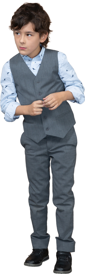 Vista frontal de un chico lindo con traje gris mirando algo con interés