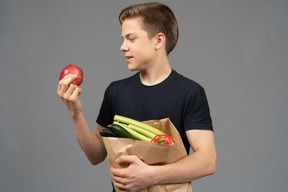 Junger mann, der roten granatapfel betrachtet