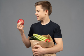 Jeune homme regardant la grenade rouge