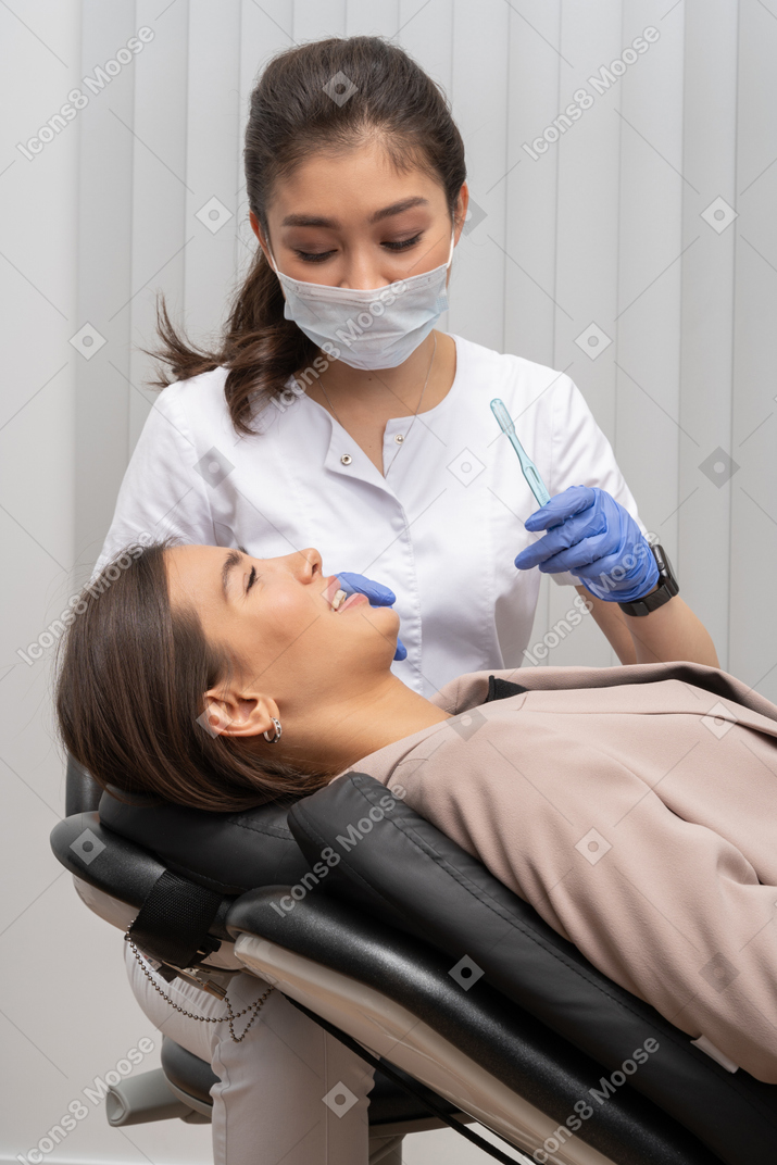 A female dentist holding a toothbrush and a smiling female patient