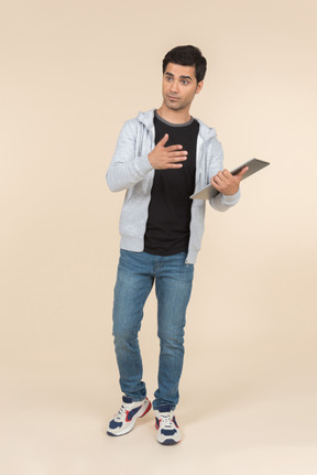 Jovem homem caucasiano apontando para um tablet digital que ele está segurando