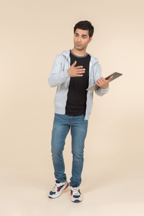 Young caucasian man pointing at a digital tablet he's holding