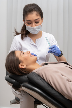 Uma dentista segurando uma escova de dentes e uma paciente sorridente