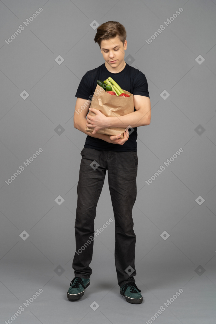 Young man looking at paper bag in his hands