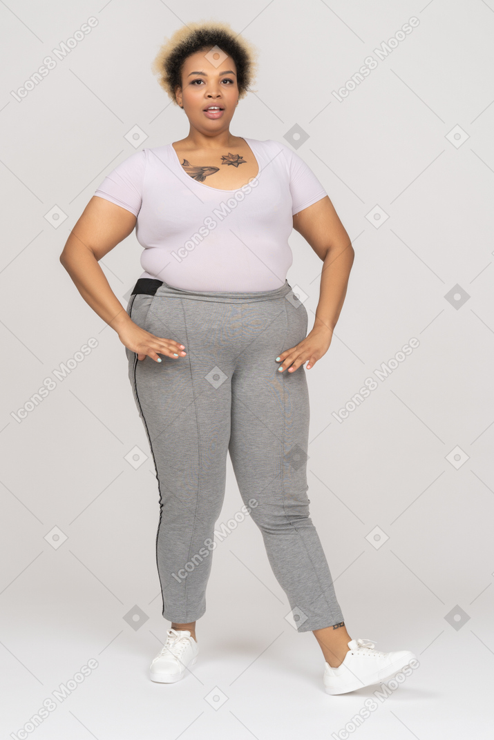 Mulher afro rechonchuda posando com legging esporte e camiseta branca