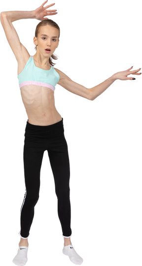 Front view of a teen girl in sportswear raising hands and opening mouth