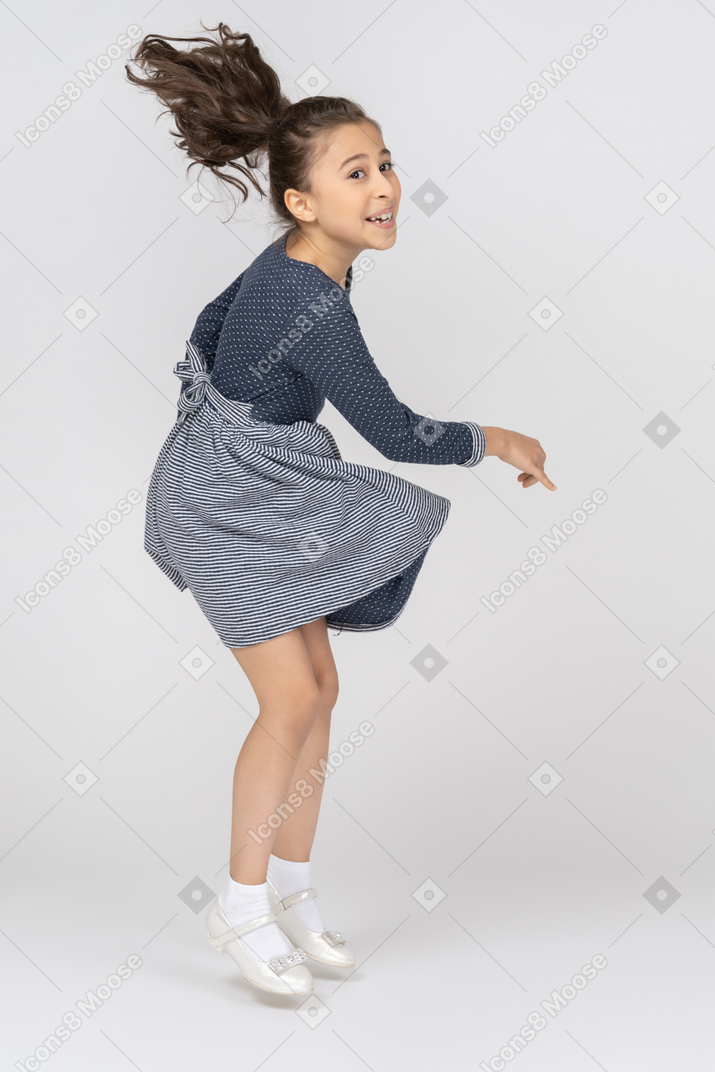 Vista di tre quarti di una ragazza che balla e salta con un sorriso felice