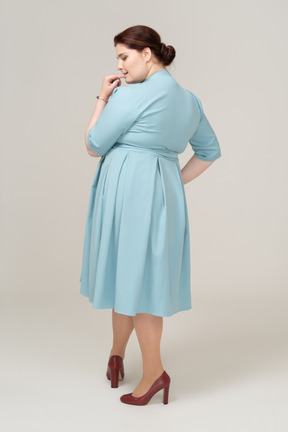 Rear view of a woman in blue dress biting her finger
