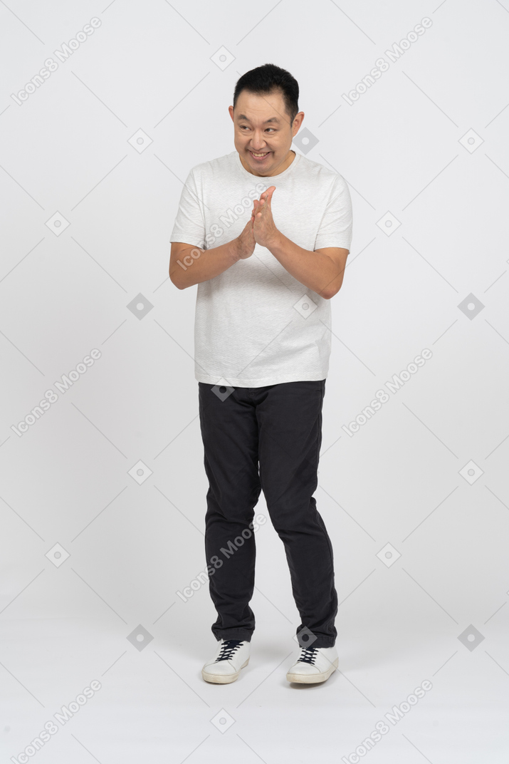 Front view of a happy man in casual clothes rubbing hands