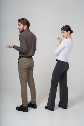 オフィス服で質問している若いカップルの4分の3の背面図