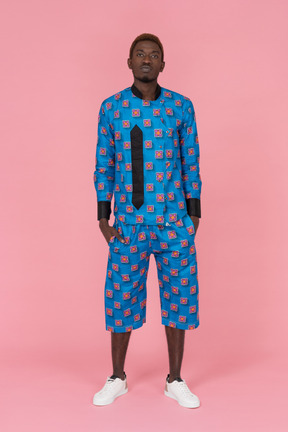 Black man in blue pajamas standing on pink background