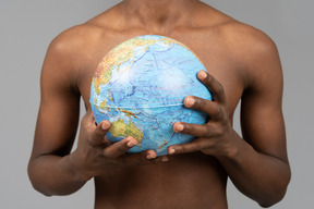 A shirtless young man holding the earth globe