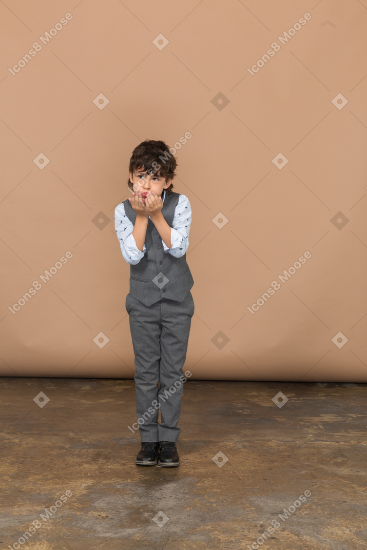 Vista frontal de um menino tímido de terno cinza