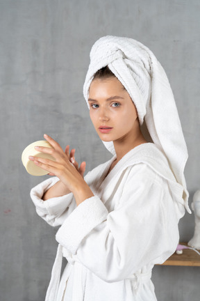 Mujer en bata de baño aplicando crema de manos