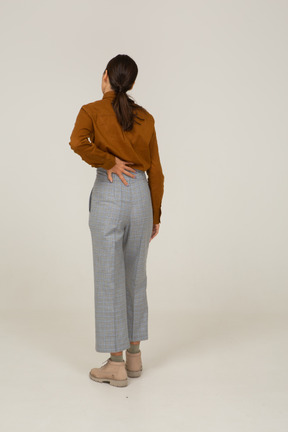 Back view of a young asian female in breeches and blouse touching back