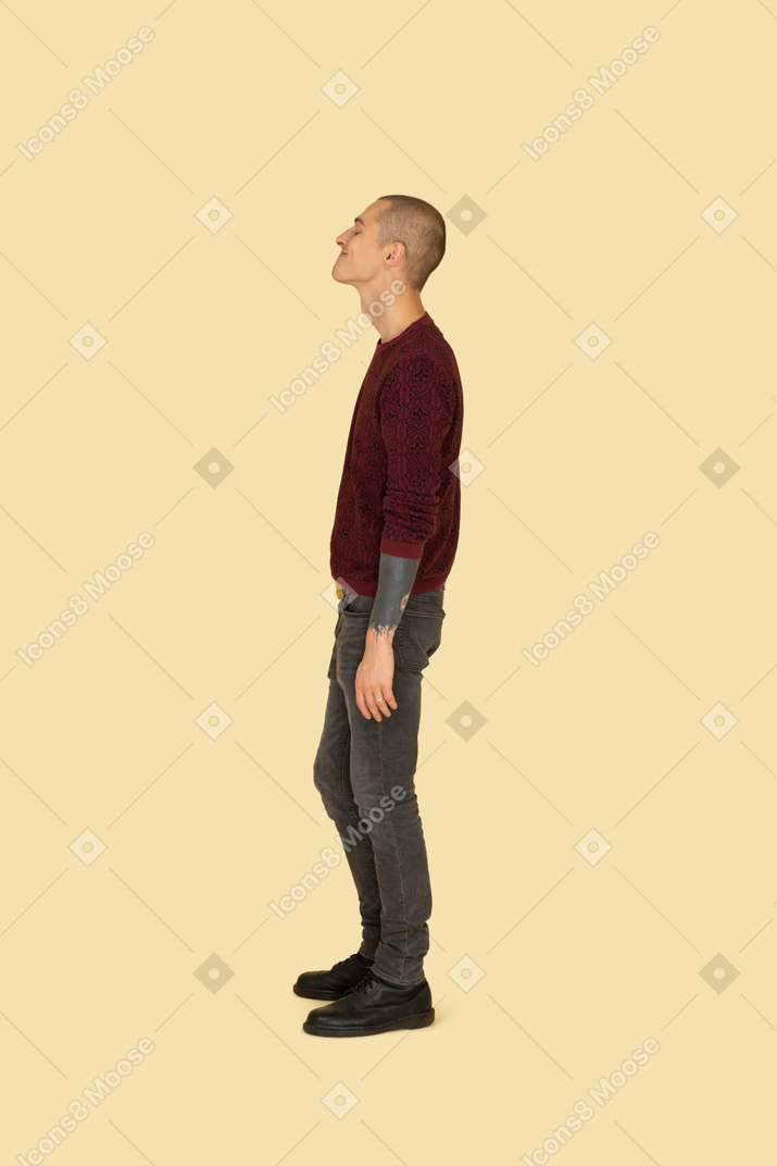 Vista laterale di un giovane uomo che fa smorfie divertente in maglione rosso