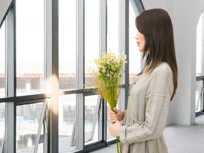 A woman holding a bouquet of flowers in front of a window