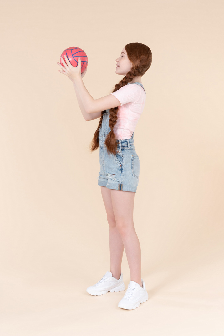 Teenage girl standing half sideways and holding ball