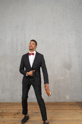 Intoxicated man in suit staggering with a bottle in his hand