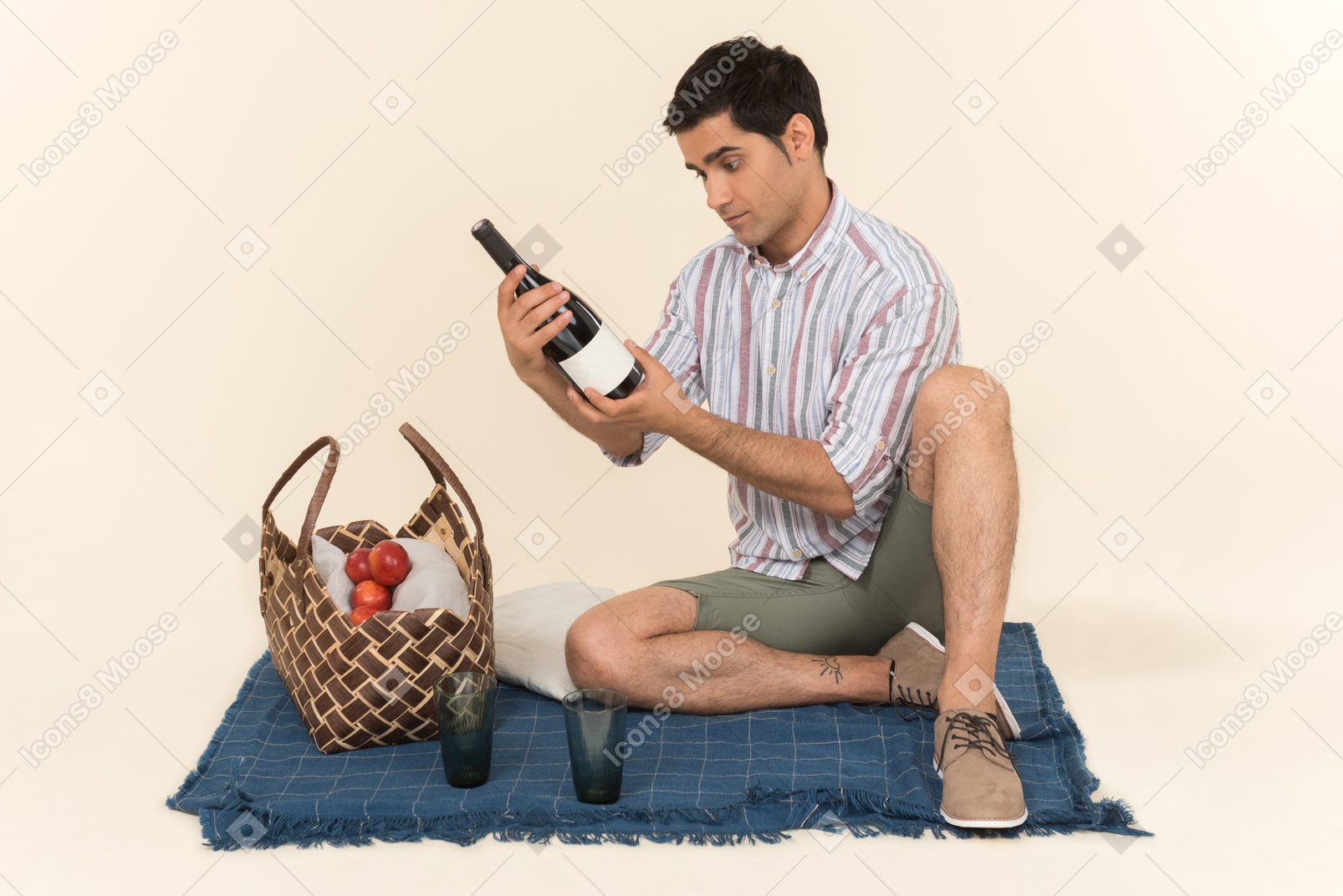 Young caucasian guy sitting on blanket and looking at bottle