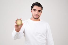 Handsome young man holding an iota coin