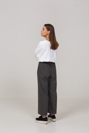 Three-quarter back view of a serious young lady in office clothing looking aside