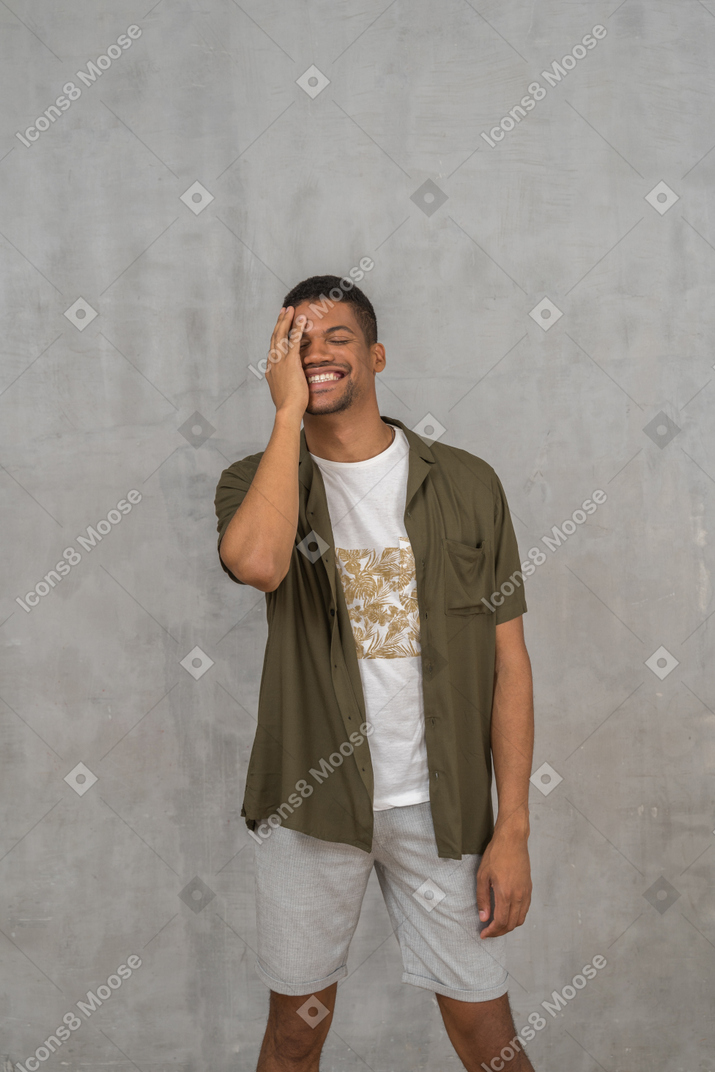 Smiling man covering his face with hand