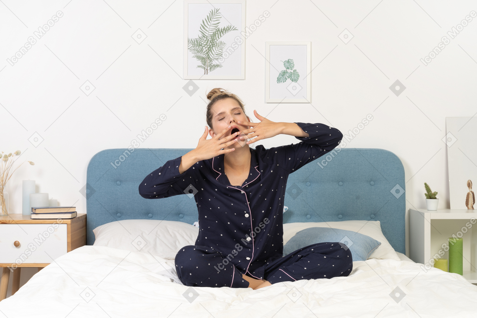 Front view of a yawning young woman in pajamas staying in bed and hiding face