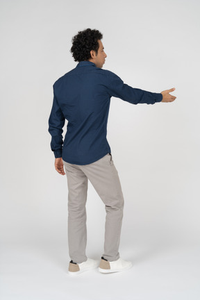 Rear view of a man in casual clothes pointing with a hand