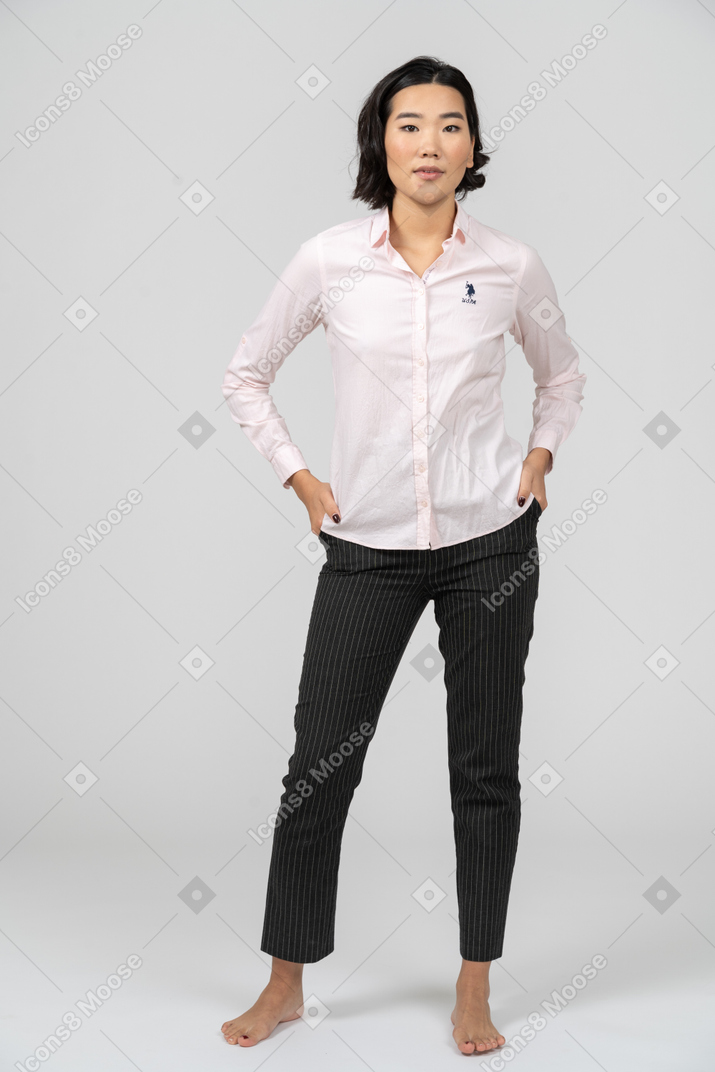Femme en tenue de bureau posant avec les mains sur les hanches