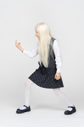 Side view of a schoolgirl beckoning with finger