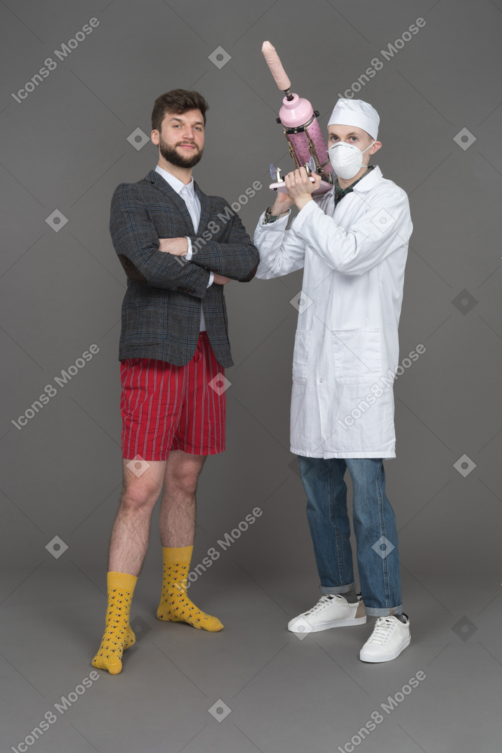 Young man and doctor with sex machine looking at camera