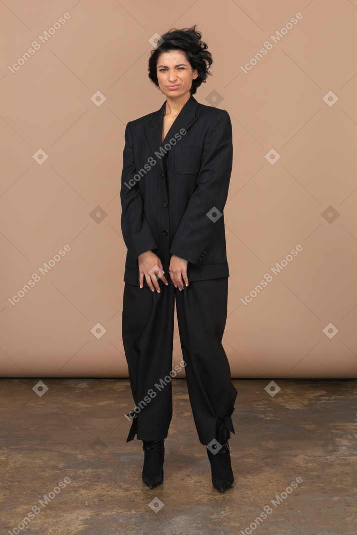 Vista frontal de uma mulher descontente em um terno preto olhando para a câmera