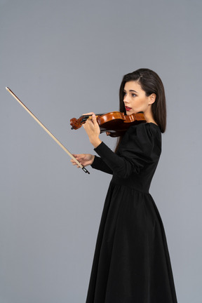 Close-up de uma jovem de vestido preto tocando violino