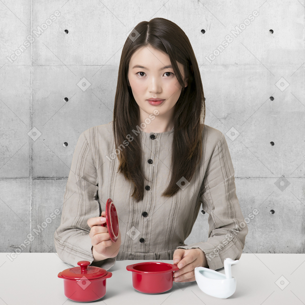 A woman sitting at a table with two red pots
