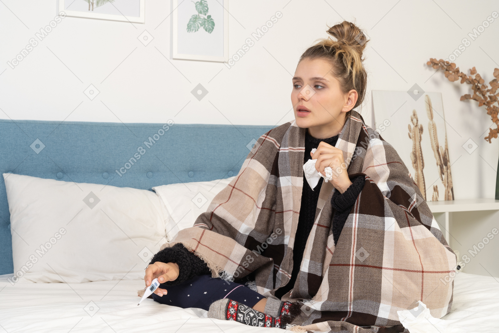 Front view of an ill young lady in pajamas wrapped in checked blanket in bed