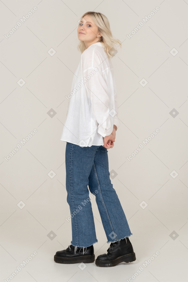 Vista lateral de uma mulher loira brincalhona com cabelo bagunçado, olhando para a câmera