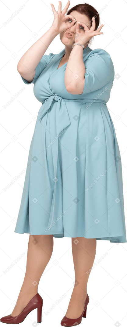 一个穿蓝色裙子的女人透过假想的双筒望远镜看的前视图