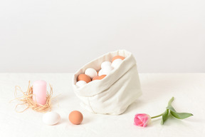 Leinentasche mit ein paar eiern, einer kerze und einer tulpe