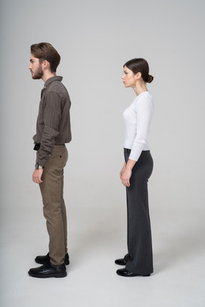 一对年轻夫妇在办公服装站着不动的侧视图